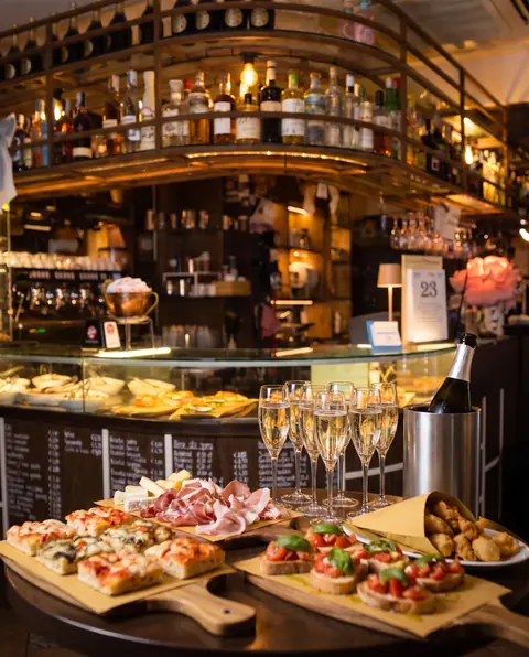 Il bancone del bar preparato per un aperitivo, con pizza, taglieri, bruschette e flûte di spumante
