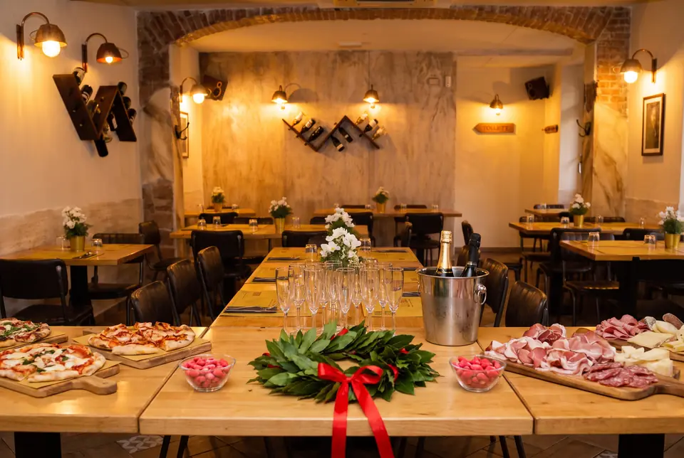 Una tavolata apparecchiata per una festa di laurea nella sala del Bistrot, con la corona d'alloro, i confetti rossi e lo spumante in fresco